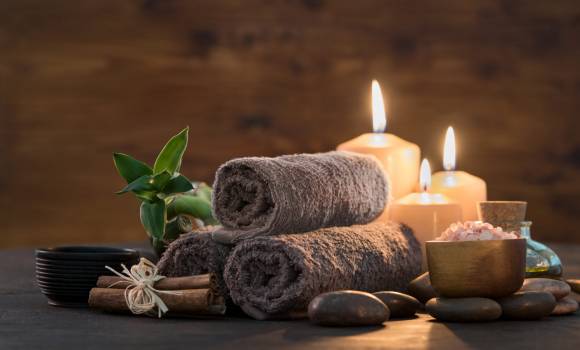 Brown towels with bamboo and candles for relax spa massage and body treatment. Beautiful composition with candles, spa stones and salt on wooden background. Spa and wellness setting ready for beauty treatment.